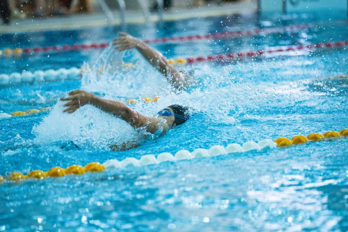 Dynamic shot of swimmers racing in a competitive swimming pool, emphasizing speed and skill.