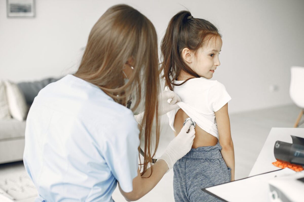 service-04 A female doctor uses a stethoscope to examine a child in a medical examination room.